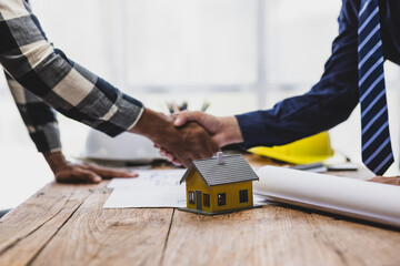 Architects and engineers collaborate on construction projects. Two man are shaking hands over a...