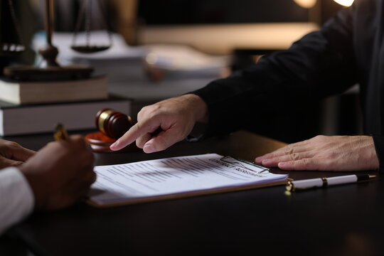 Lawyer reviewing contract agreement with legal documents, Discussing contract agreement at desk with legal document.
