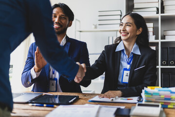 Business people shaking hands during meeting. Diverse business team shaking hands in office, collaborating.
