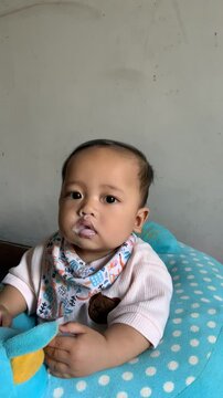 A 6-month-old baby boy learning to eat, being gently spoon-fed by his mother at home. Capturing a sweet bonding moment during a mealtime milestone.