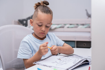 Junge mit Farbstiften malt im Kinderzimmer