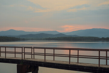 The concrete walkway into the water reservoir with the horizontal line of the mountains during the sunset