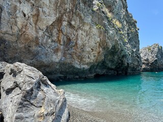rock in the sea Coastal scene with gentle waves washing against a rocky shore under a soft light....