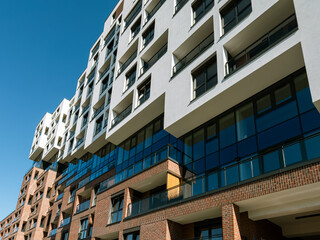 Obraz premium Contemporary residential architecture in South Spain featuring geometric balconies, large windows, and a mix of brick and glass, ideal for real estate and urban living concepts.