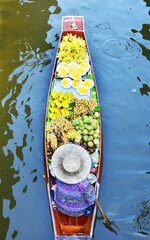 A vendor is rowing a boat to sell fruit in a canal at Damnoen Saduak Floating Market, the most famous floating market in Thailand.