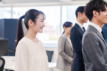朝会で笑顔で話を聞くオフィスワーカー