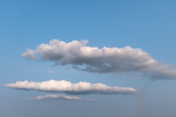 Layered clouds float across a blue sky, touched by light and shadow. A visual metaphor for the soul’s journey — suspended between hope, faith, and gentle introspection.