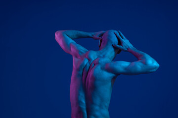 Obraz premium A contemplative man with a muscular build, showcasing a striking black and white aesthetic. The image highlights deep emotions against a vibrant background.