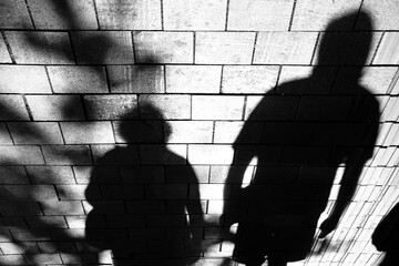 Shadow silhouette of people walking city street sidewalk in black and white high contrast