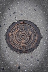 Circular drainage cover with industrial design on sidewalk