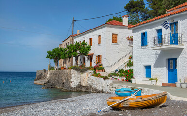 white house with colorful shutters of a seaside village with boats on the beach in Peloponnese Greece