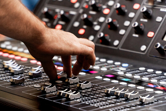Close up of sound technician moving faders of the soundboard during a summer music festival