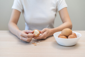 Protein in food, keto diet asian young woman hand peeling, shelling chicken boiled egg, prepares...