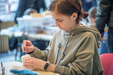 Concentrated student using needle felting technique creating handmade product during a workshop, developing her creativity and fine motor skills