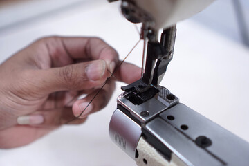 Threading the needle through the eye of a sewing machine specifically in the garment industry