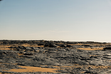 Ash-covered hills in Egypt's Black Desert under a clear sky, scenic and remote landscape. Volcanic	