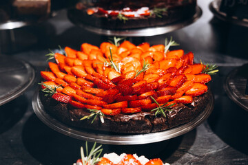 Cheesecake decorated with fresh strawberries displayed in bakery shop window.