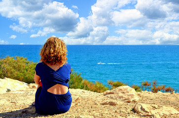 Curly-haired blonde woman looking at the sea in Torredembarra, Tarragona