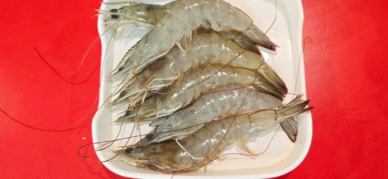Pacific white shrimp or white leg shrimp are arranged in a square tray put on red floor. for serving in Shabu restaurants or barbecue restaurants. The shrimp are translucent, thin shells. easy to peel