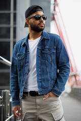 Fototapeta premium Young black man in street wear and sunglasses standing outdoors