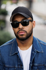 Obraz premium Bearded african american man in sunglasses and baseball cap outdoors
