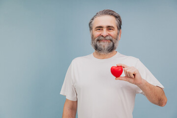 Senior man holding small red heart promoting health and wellness