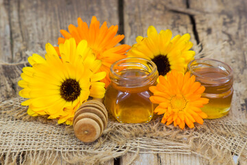 honey and calendula flowers on wooden background