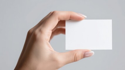 Obraz premium Hand holding a blank white card against a neutral background