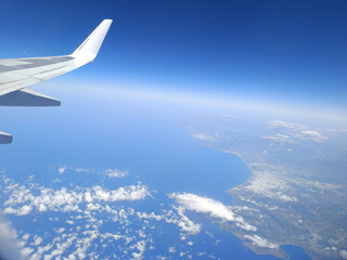 Coastal aerial view from airplane window flying above deep blue sea