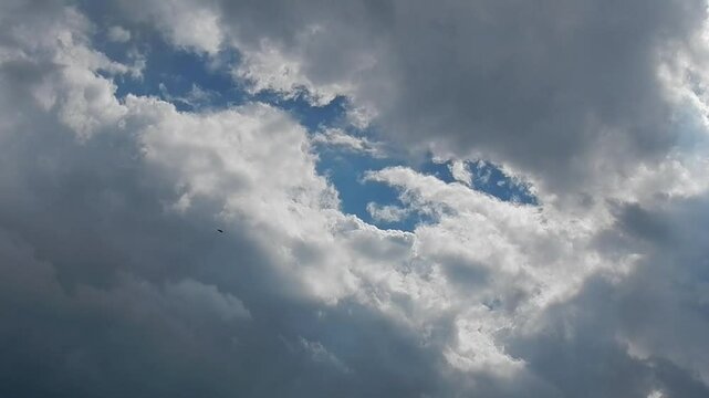 Natural sky background with moving grey Stratocumulus clouds and white Cumulonimbus calvus and sun rays. Topics: weather, weather change, rainy, sunny, cloudscape, meteorology, air space, climate