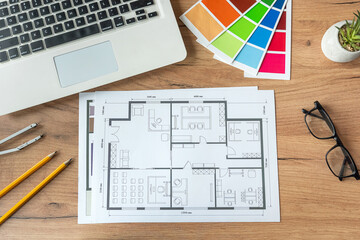 color palette and drawing blueprint of house, laptop computer on office desk.