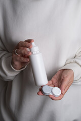 Contact lenses, case and bottle with solution and eye drops on white background. Eye health and care, vision, ophthalmology concept, close-up 