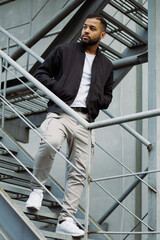 African american man in street wear walking on fire escape