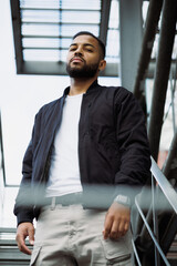 Portrait of african american man in bomber jacket looking at camera on fire escape