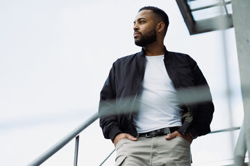 African american man in bomber jacket walking on fire escape
