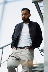 African american man in bomber jacket walking down on fire escape