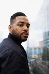 Portrait of african american man in bomber jacket looking at camera outdoors