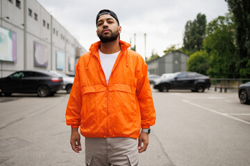Confident african american man in windbreaker jacket looking at camera on city street