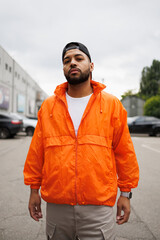 Confident african american man in windbreaker and baseball cap on urban street