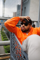 Stylish african american man in sunglasses sitting in shopping cart on urban street