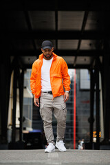 African american man in stylish windbreaker jacket and baseball cap walking on street © Dmytro Hai