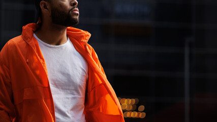 Part of african american man in bright windbreaker jacket standing on street