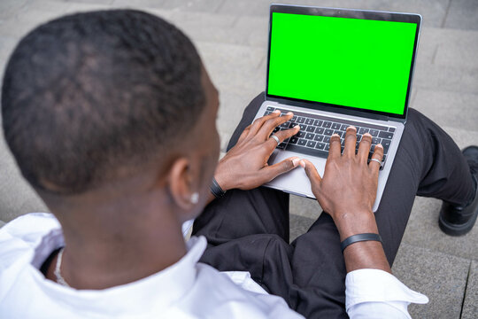 Businessman working on laptop with green screen outdoors - Powered by Adobe