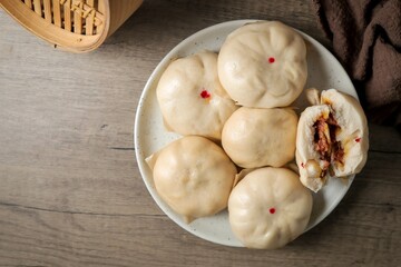 steamed stuff bun,steamed dumpling,stuffed steamed bun,thai called sarapao, in white plate on wooden background