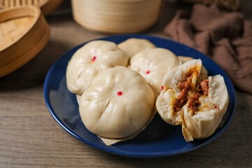 Steamed stuff bun,steamed dumpling,stuffed steamed bun,thai called sarapao, in blue  plate on wooden background