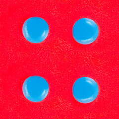 Seamless 4k photo texture material of red colored plastic with blue buttons.