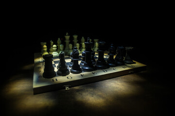 Chess board game concept of business ideas and competition. Chess figures on a dark background with smoke and fog.