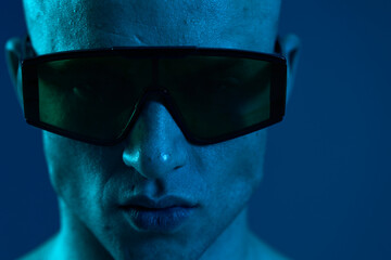 Close-up of a man wearing sunglasses, showcasing striking expression in a cool blue tone,...
