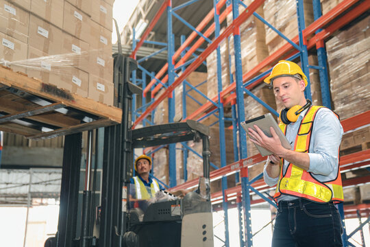 Smart caucasian warehouse man,manager use digital tablet check package with worker forklift driver loading box on shelf, product distribution inventory management, Logistics shipping business planning - Powered by Adobe