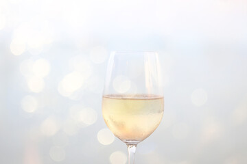 a glass of white wine, a background under the summer sun, a bokeh and sun glare, a blurred abstract...